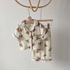 two baby clothes hanging from a wooden hanger