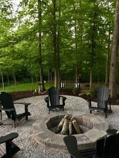 an outdoor fire pit surrounded by chairs and trees