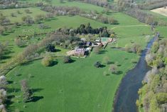 an aerial view of a large house in the middle of a green field with trees