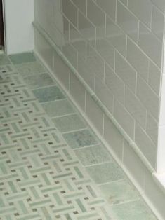 a cat sitting on the floor next to a toilet in a room with tiled walls