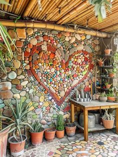 a heart made out of rocks on the side of a wall next to potted plants