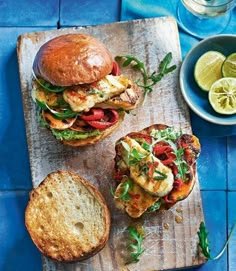 two sandwiches on a cutting board with lemons and water