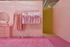 a pink room with clothes hanging on the rack