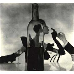 an old photo of a woman sitting in a chair next to a bottle with water