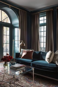 a living room with blue couches and curtains on the window sill, coffee table in foreground