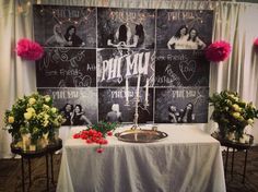 a table with flowers and candles on it in front of a chalkboard wall that has pictures