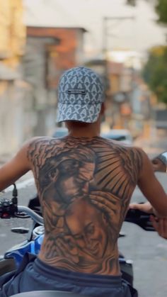 a man with tattoos on his back sitting on a motorcycle