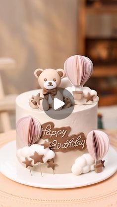 a birthday cake decorated with teddy bears and hot air balloons for a baby's first birthday