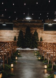 the aisle is lined with wooden chairs and lit candles in front of christmas trees on display