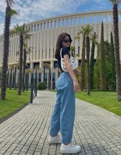 a woman standing in front of a building with palm trees and blue skies behind her