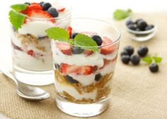 two glasses filled with fruit and yogurt on top of a table