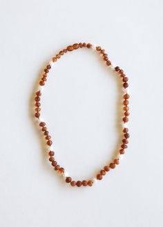 a beaded necklace with white and brown beads on a white background, showing the clasp