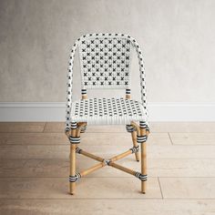 a white wicker chair sitting on top of a hard wood floor next to a wall