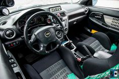 the interior of a car with black leather seats and green dash tape around the steering wheel