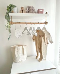 a baby's clothes hanging on a shelf next to a bag