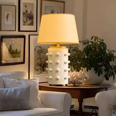 a lamp that is sitting on a table in a room with pictures and furniture around it