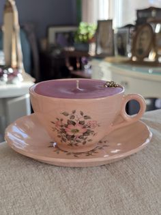 a pink teacup with a lit candle in it