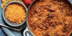 two bowls filled with chili and cheese next to nachos