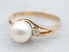 A little twist on a classic, this pearl ring has a beautifully polished yellow gold band and a small but sparkling accent diamond! The band has a simple and fluid design, and the creamy white cultured pearl with grey undertones and makes the perfect understated piece.Metal: 14K Yellow GoldGem: PearlGem Measurements: 6.8 mm, RoundAccents: Diamond .02 Carats, SI in Clarity, G in ColorRing Size: 6.50Marks: “585 14K” Stamped on the inside band Luxury Delicate Yellow Gold Pearl Ring, Pearl Ring Design, Yellow Gold Amethyst Ring, Gold Amethyst Ring, Gold Pearl Ring, Pearl And Diamond Ring, Gold Signet Ring, Vintage Pearls, Color Ring