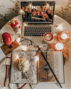 an open book sitting on top of a table next to a laptop computer and candles