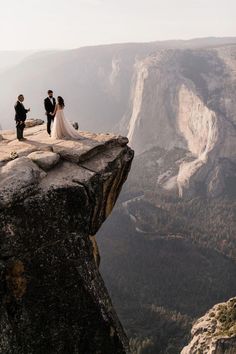 a bride and groom standing on top of a cliff