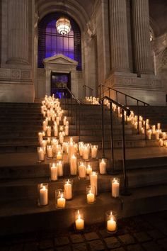 many lit candles sit on the steps in front of a building with columns and windows