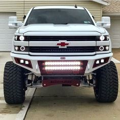 a white truck parked in front of a house with lights on it's hood