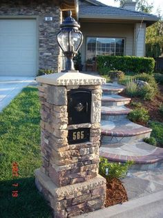 a mailbox in front of a house with steps leading up to it and a lamp on top