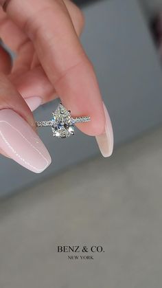 a woman's manicured nails with a ring on top of her finger and a diamond in the middle