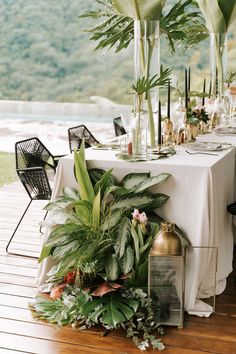 the table is set up with plants and candles for an outdoor wedding reception or special event