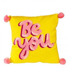 a yellow pillow with pink pom - poms on it that says be you