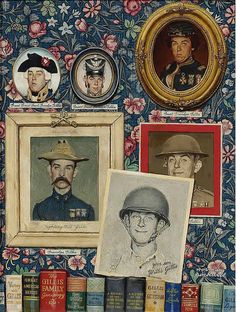 several framed pictures and portraits on a wall with books in the foreground, including two men's heads