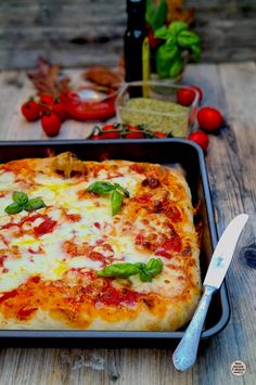 a square pizza sitting on top of a pan next to a knife and pepperoni