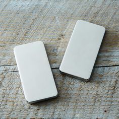 two white electronic devices sitting on top of a wooden table with no one around them