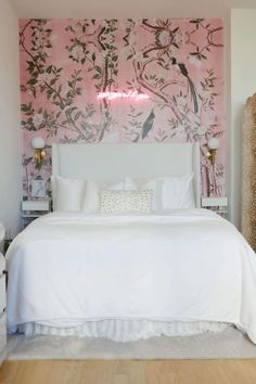 a white bed sitting in a bedroom next to a pink wall