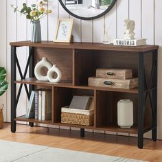 a wooden shelf with books, vases and other items on it in front of a mirror