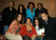 a group of people sitting next to each other in front of a wall smiling at the camera