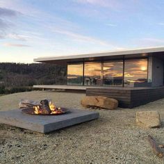 a fire pit sitting on top of a gravel field next to a large glass window