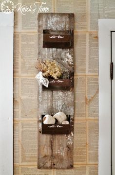 an old book shelf with some shells and flowers on it in front of a wall