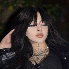 a woman with long black hair and piercings on her face, wearing a leather jacket