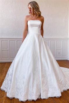 a woman in a white wedding dress standing on a wooden floor