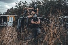 a woman is sitting on the hood of an old pickup truck with her head stuck in weeds