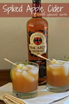 two glasses filled with apple cider sitting on top of a table