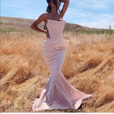 a woman in a pink dress is posing for the camera with her hands on her head