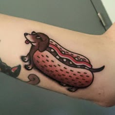 a person with a tattoo on their arm has a dog and hotdog in it