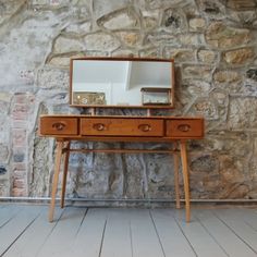 a wooden table with a mirror on top of it next to a brick wall and floor