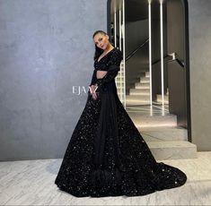 a woman in a black gown standing on stairs with her hand on her hip and looking off to the side