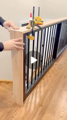 two people are working on a gate in a room with hard wood flooring and white walls