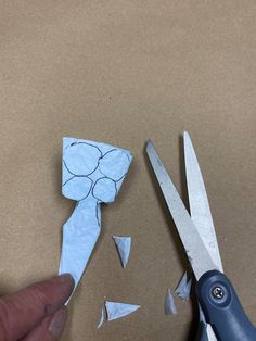 a pair of scissors cutting paper into small pieces with one cut out and the other broken