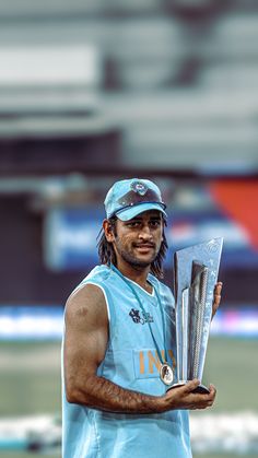 a man holding up a trophy in his right hand and wearing a baseball cap on top of his head